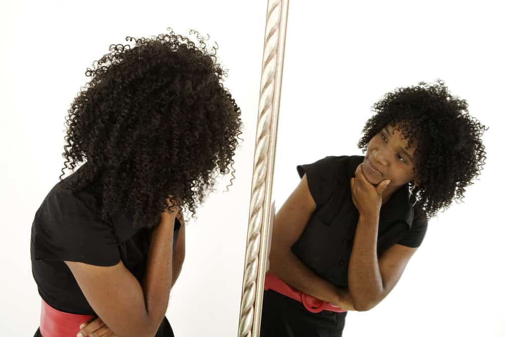 self aware colored woman looking in mirror